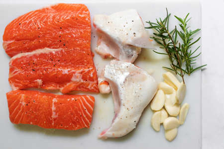 Fresh salmon with rosemary, garlic and spice on cutting board for delicious salmon steak. Top view.