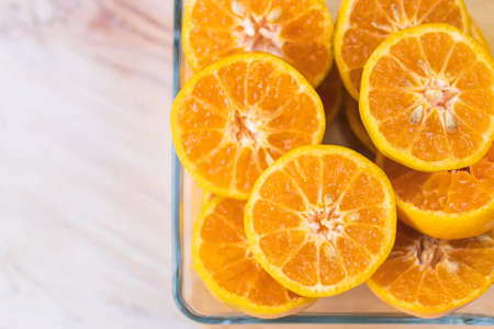 Fresh orange fruits in glass tray on wooden table. Top view with copy space.の写真素材