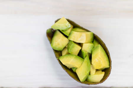 Sliced avocado isolated on white wooden table background; top view.