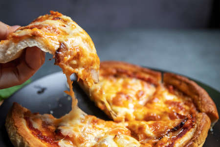 Hand take homemade pizza with guanciale on black background. Homemade delicious pizza.の写真素材