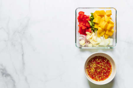 Ripe mango, bell pepper, culantro garlic, onion and spicy sauce on table top view and copy space. Ingredient for delicious mango spicy salad.の写真素材
