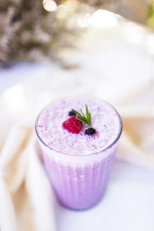 Blueberry and strawberry smoothie in glass with soft sunlight in garden background.の写真素材