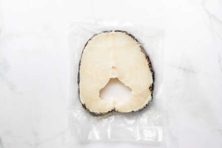 Snow fish in vacuum package for delicious good meal. Snow fish are found in the deep ocean, thick flake and melt-in-your-mouth texture. Isolated on white marble table background.の写真素材