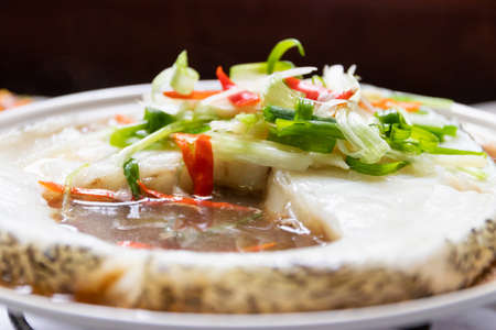 Steamed snow fish with soy sauce. Snow fish, soy sauce, ginger, scallion and chili. Top view on white table background.の写真素材