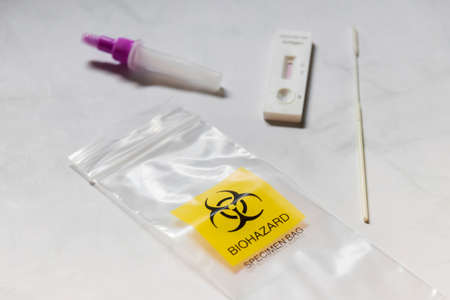 Covid-19 Rapid Antigen Test kit and biohazard specimen bag on white background. Concept of waste separation to prevent spreading of coronavirus infection.の写真素材