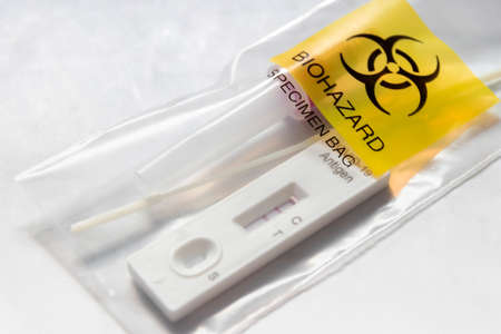 Covid-19 Rapid Antigen Test kit and biohazard specimen bag on white background. Concept of waste separation to prevent spreading of coronavirus infection.の写真素材