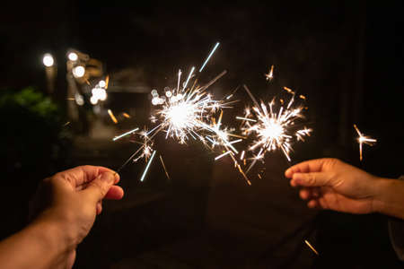 Hands holding with fire sparklers together to celebrate the night and the new start. Happy new year. Happy holidays.の写真素材