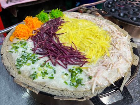 Tradition Thai street dessert; Thai coconut rice pudding (Khanom Krok). Street vendor made coconut rice pancake with many toppings.の写真素材