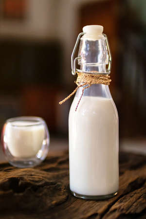 Milk in a bottle and glass of milk on wooden background.の写真素材