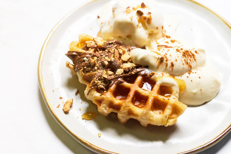 Croffle served with ice-cream, soft whipped cream, chocolate sauce and almond crushed on plate. (Croffle is croissant and waffle). Mix and match menu.の写真素材