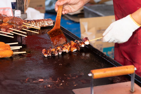 Delicious seafood octopus tentacles skewers grilling on griddle pan. Traditional food stall in Japan.の写真素材