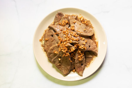 Fried pork liver with garlic on white plate.