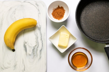 Ingredient for fried bananas with honey cinnamon butter sauce; Cavendish bananas, cinnamon, butter and honey. Top view on white table background. Make this easy banana dessert reciの写真素材