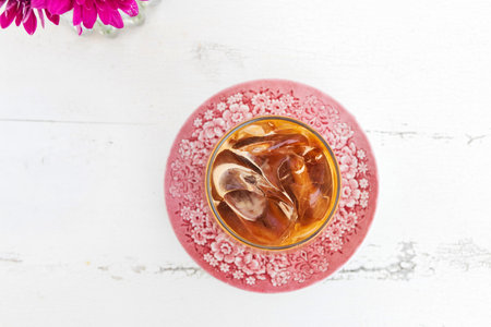 Glass of iced caramel macchiato on white wooden table with blue sea on background.