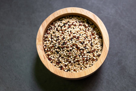 Pile of mixed raw quinoa (Three colors) in wooden bowl on grey background. Quinoa provides protein, dietary fiber, B vitamins, and dietary minerals in rich. Super food of life.の写真素材
