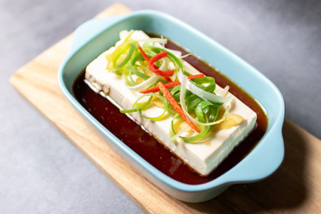 Vegan silken tofu is served hot or cold with a savory soy sauce flavored with sesame oil, ginger and green onions .の写真素材