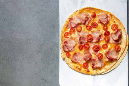 Delicious gourmet pizza with smoke bacon and cheese on board with black table background. Homemade delicious pizza. Top view and copy space.の写真素材