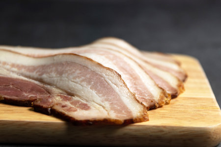 Guanciale dried speck Ð° ham. Italian cured meat product prepared from pork jowl or cheeks sliced on wooden board.の写真素材