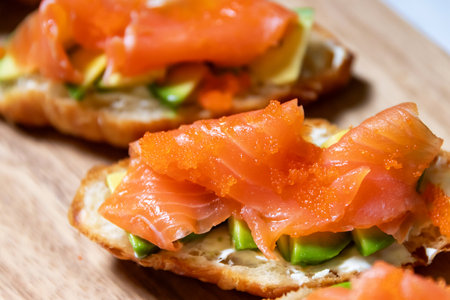 sandwiches with salmon, avocado on wooden boardの写真素材