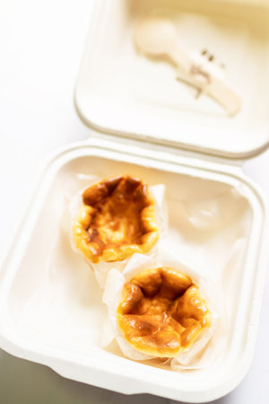 Mini Basque Burnt Cheesecake in paper food container. Top view and copy space on white table...