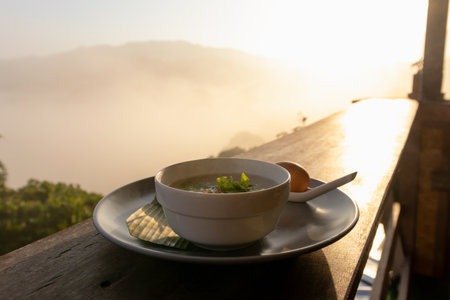 Breakfast table on rustic wooden terrace with fog on mountains in morning sunrise background.