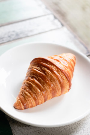 French croissant on plate on vintage wooden table background.の写真素材