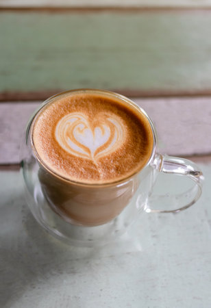 Cup of coffee with latte art on vintage wooden table background.の写真素材