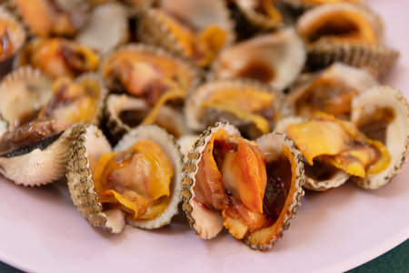 Cooked cockle on plate usually serve with spicy seafood sauce, menu from sea shell. Semi-cooked raw...