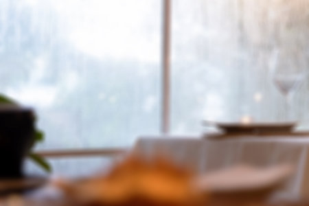 Blurred background of table settings for fine dining with flower and glassware at restaurant with bokeh light for background uses.の写真素材