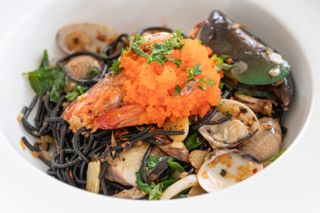Squid ink spaghetti with garlic, olive oil, chili and seafood on white dish.
