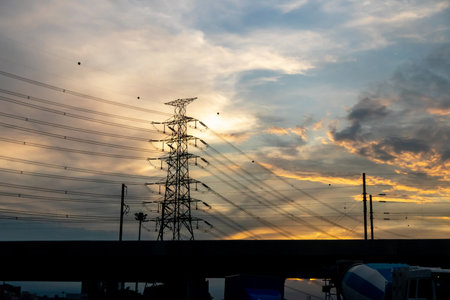 High voltage pole silhouette on sunset sky background.