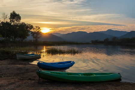 Beautiful landscape with reflection of mountain range on water during sunset at Tha Khoei reservoir in Ratchaburi, Thailand.の写真素材