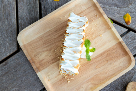 Delicious dessert on a wooden plate, featuring creamy filling and decorative topping, perfect for...