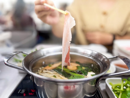 A person enjoying hot pot with fresh ingredients, showcasing the vibrant colors and textures of a...