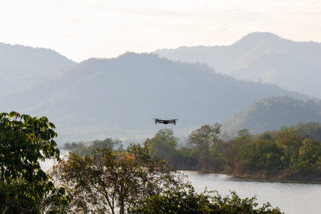 A drone flying above a serene river landscape surrounded by mountains, capturing stunning views of...