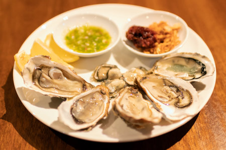 Fresh oysters served on a plate with lemon and dipping sauces, perfect for seafood lovers seeking a...