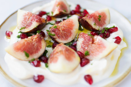 Delicious fig healthy garnished with pomegranate on greek yogurt and virgin olive oil.の写真素材
