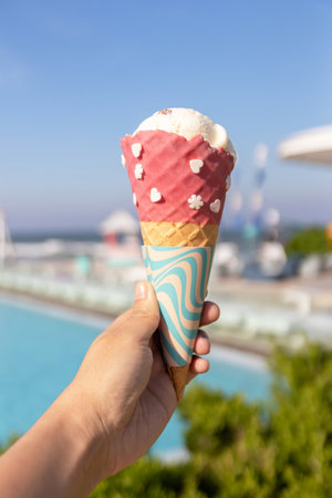 Woman hand holding ice-cream cone for refreshing with summer background.