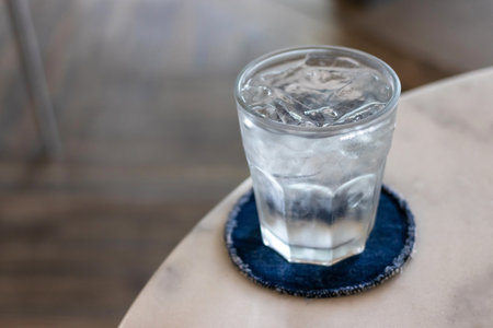Glass of water with ice cubes on wooden table.の写真素材
