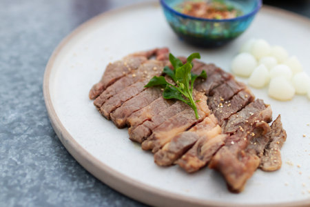 Deliciously sliced beef served on a plate with dipping sauce and garnish.の写真素材