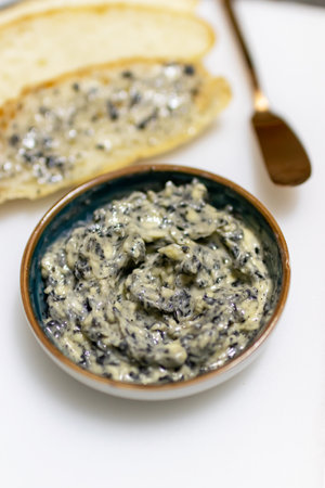 Delicious creamy spread with herbs served in a bowl and accompanied by bread.