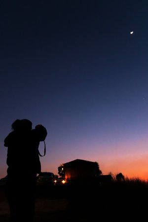 The photo shows a silhouette of a man standing as the sun sets in the background.の写真素材