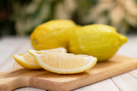 Close-up photo of a lemon cut into wedges on a wooden table.の写真素材