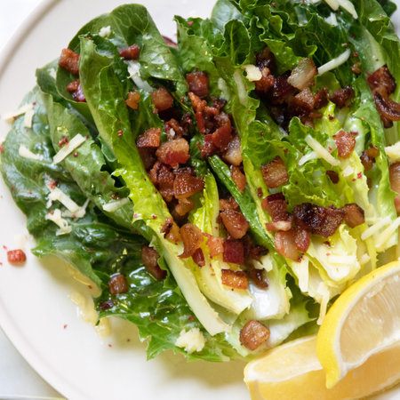 Fresh romaine lettuce topped with crispy bacon and lemon, creating a delicious and vibrant salad dish for any meal.の写真素材