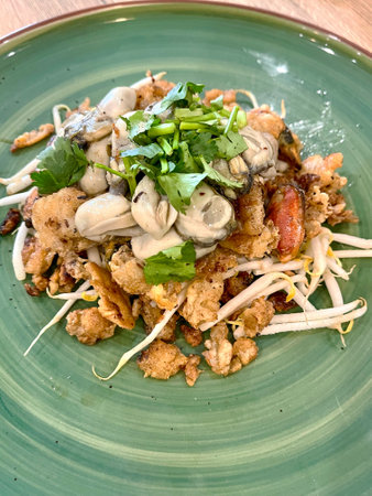 Delicious seafood dish topped with fresh herbs, vibrant flavors, and a stunning presentation on a green plate.の写真素材