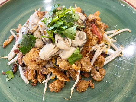 A delicious plate of fried oysters served with fresh herbs, garnished artistically on a green plate.の写真素材
