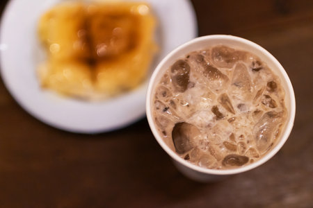 Iced chocolate with a buttery slice of toast on a white plate.