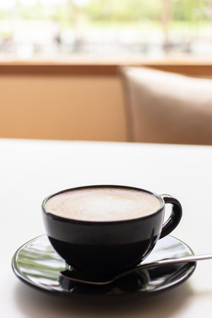 Hot coffee with milk in a black cup on white table.の写真素材