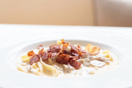 Fettucine carbonara pasta with fried bacon and grated cheese. Carbonara is an Italian pasta dish from Rome made with egg, hard cheese, pancetta and pepper.の写真素材