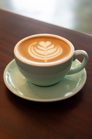 Cup of coffee with latte art on wooden table with soft sunlight.の写真素材